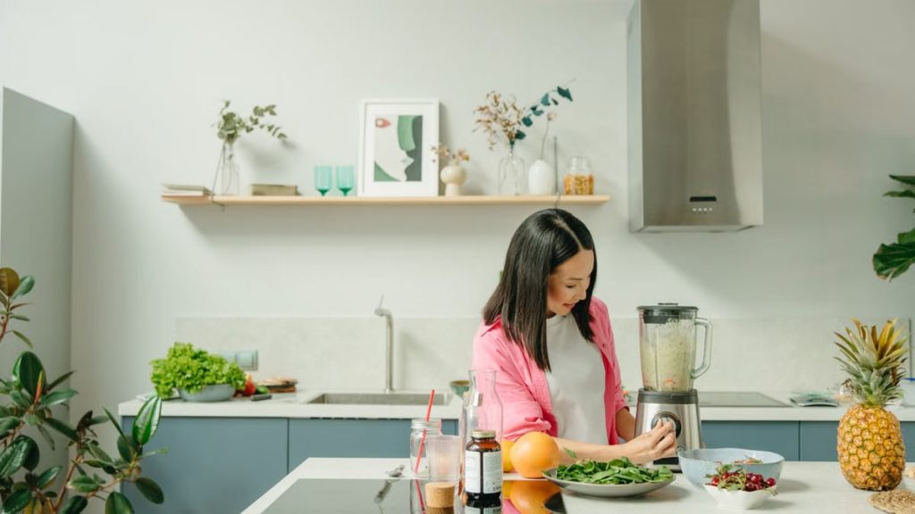 A woman blends fresh ingredients for a healthy smoothie in a stylish kitchen, promoting wellness.