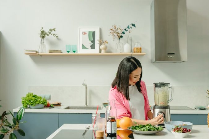 A woman blends fresh ingredients for a healthy smoothie in a stylish kitchen, promoting wellness.