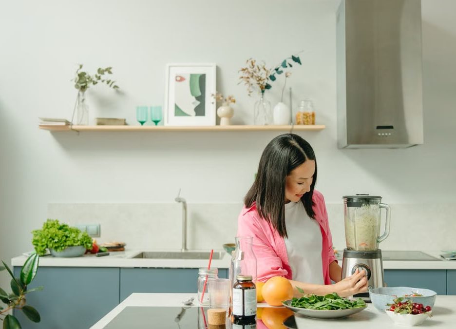 A woman blends fresh ingredients for a healthy smoothie in a stylish kitchen, promoting wellness.