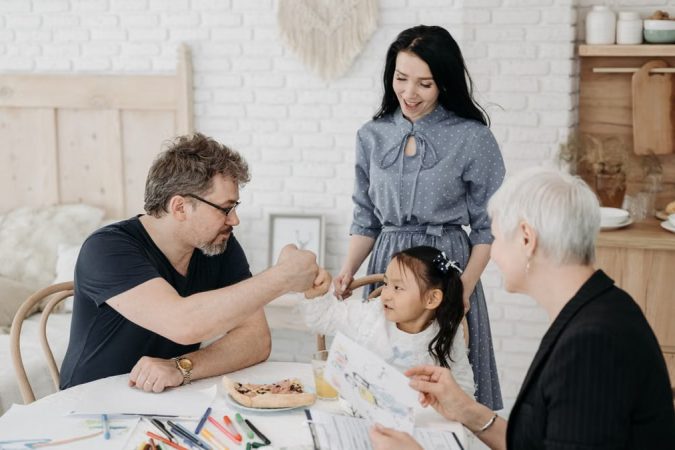 Child with foster parents and a social worker discussing adoption at home.