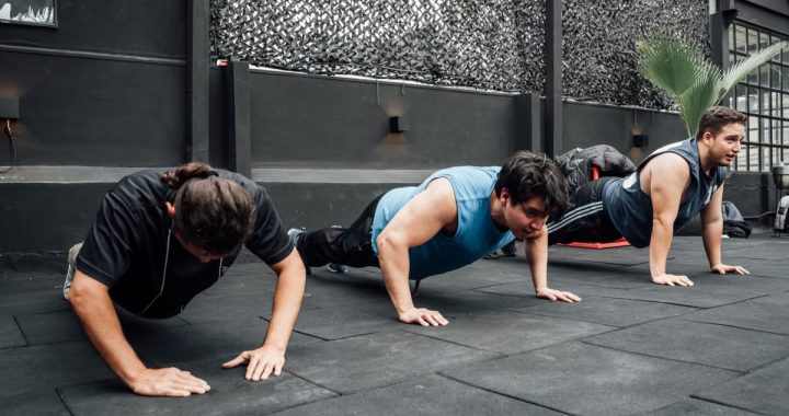 Men performing push-ups during a group workout session in Mexico City gym.