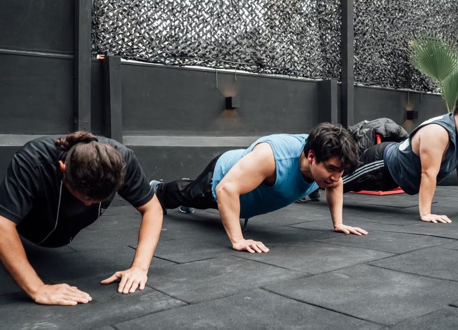Men performing push-ups during a group workout session in Mexico City gym.